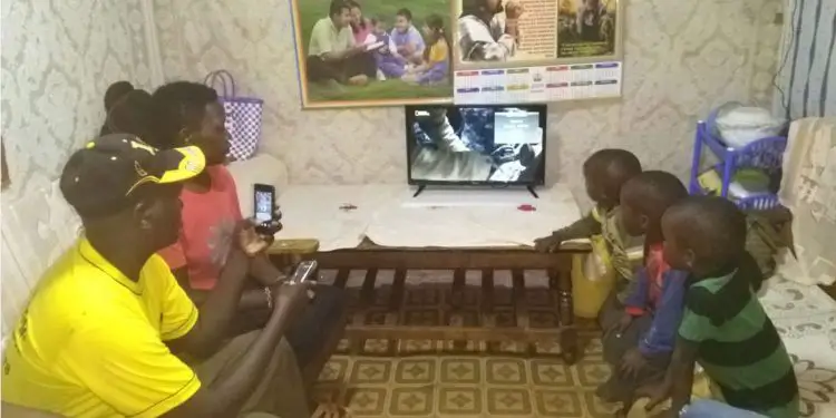 A Kenyan family enjoying the benefits of the Sun King Home 400 with a 24-inch TV