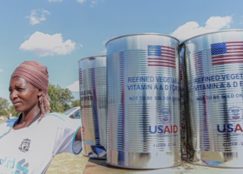 A Zimbabwean poses next to food rations from the USaid. From Zimbabwe's independence to the mid-1980s, the USA had extended funding up to US$600,000 to develop the Zimbabwean economy. www.theexchange.africa