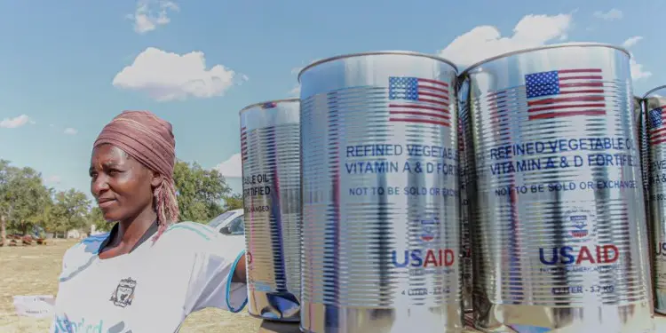 A Zimbabwean poses next to food rations from the USaid. From Zimbabwe's independence to the mid-1980s, the USA had extended funding up to US$600,000 to develop the Zimbabwean economy. www.theexchange.africa