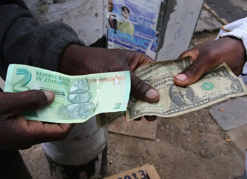 Illegal money changers pose while exchanging a new Zimbabwe bond note and U.S. dollar notes in the capital Harare, Zimbabwe. www.theexchange.africa