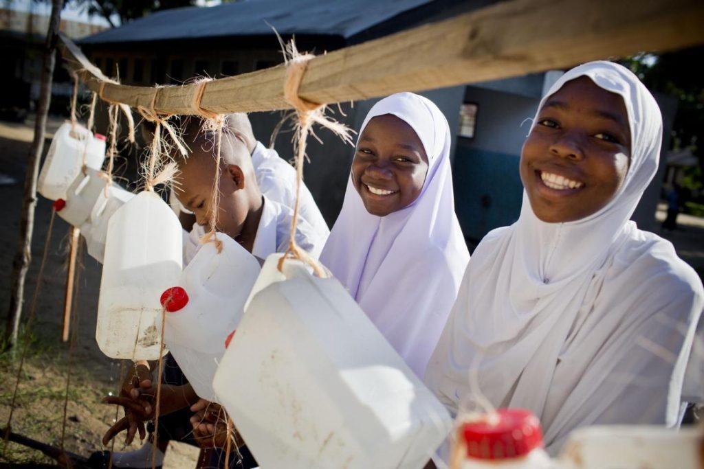 School girls wash hands using make shift water flowing taps