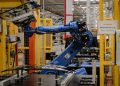 A robot arm carries a glass part on the assembly line of a factory. [Photo/AFP]