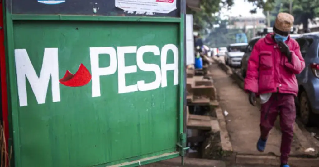 A Kenyan walks past an M-Pesa shop.https://theexchange.africa/