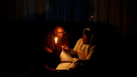Thandiwe Sithole studies by a candle while her grandmother Phumzile Sithole looks on during one of frequent power outages from South African utility Eskom caused by its aging coal-fired plants, in Soweto, South Africa. www.theexchange.africa