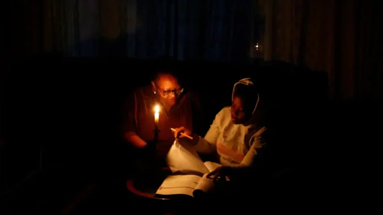 Thandiwe Sithole studies by a candle while her grandmother Phumzile Sithole looks on during one of frequent power outages from South African utility Eskom caused by its aging coal-fired plants, in Soweto, South Africa. www.theexchange.africa